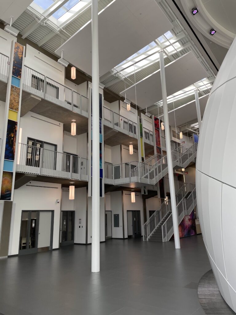 Photograph of the Science and Mathematics Complex Atrium with the edge of the planetarium sphere on one side and the floors showing offices and laboratory spaces on the other